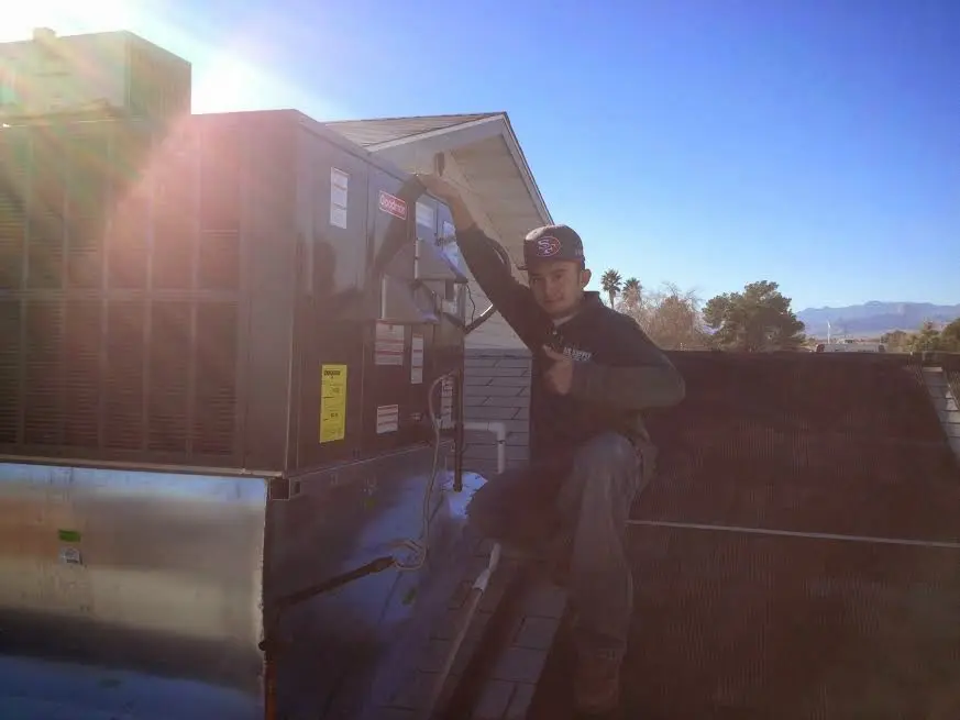 HVAC technician performing Air Duct Repair on a rooftop unit in Mesa